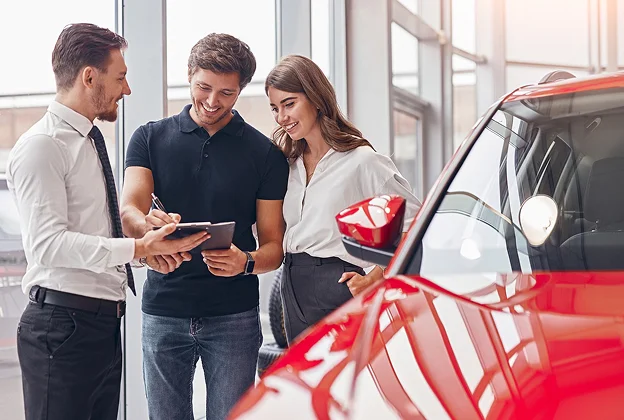 couple avec vendeur de voiture pour acheter uen voiture en concession